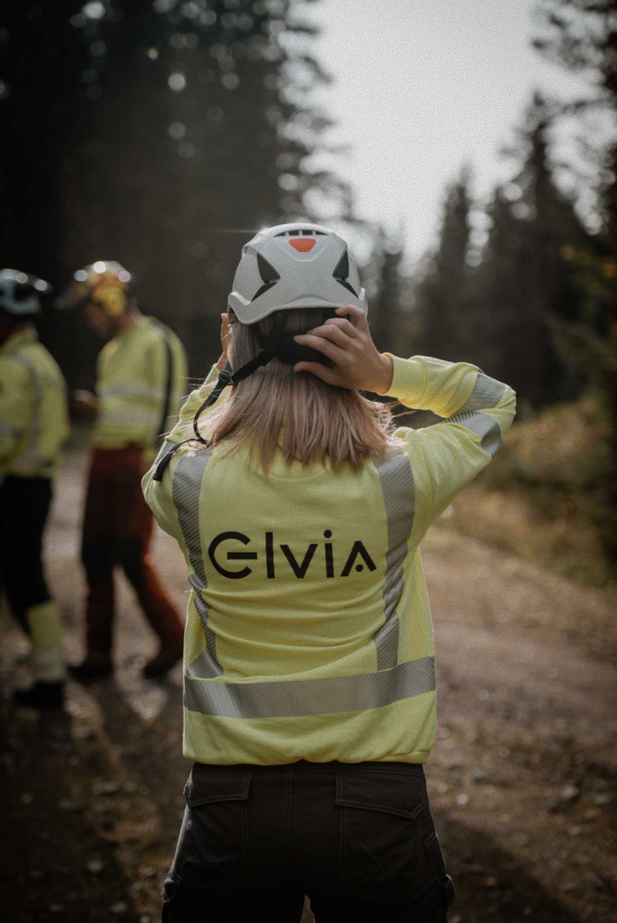 Ingeniør i Elvia-jakke fotografert bakfra ute i felten.