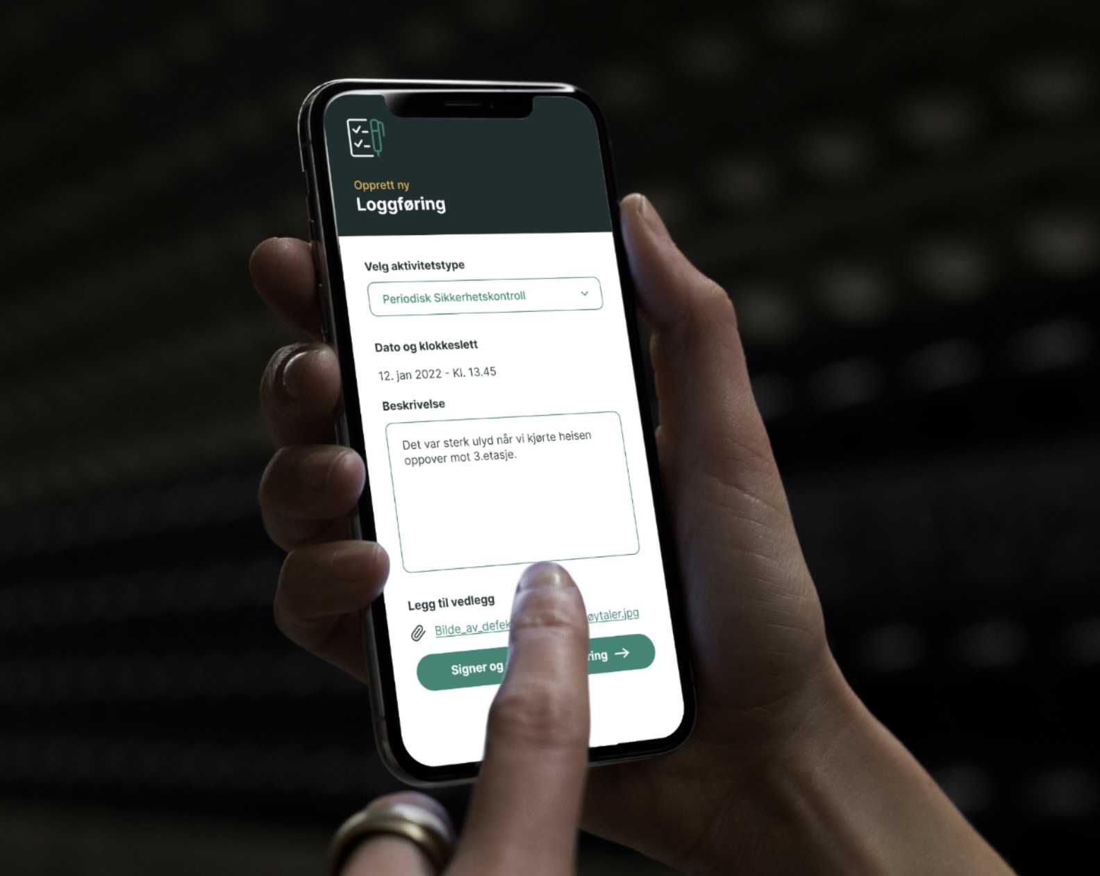 Hånd holder en mobil som viser Lilo-appen, skjema for å logge en periodisk sikkerhetskontroll.